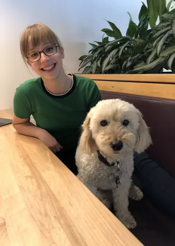 A teammate at a wooden table with a fluffy dog