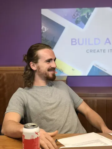 A teammate smiling at the table with a can of beer
